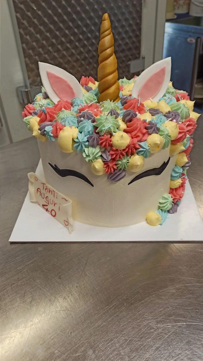 Torta unicorno con corno dorato e fiori di crema