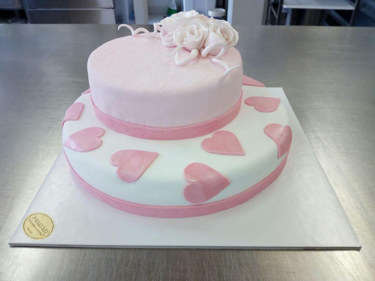 Torta a due piani rosa con cuori e rosa di zucchero