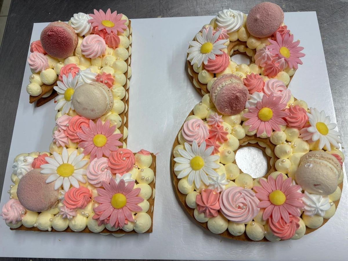 Cream tart a forma di 18 con margherite e ciuffi di crema rosa