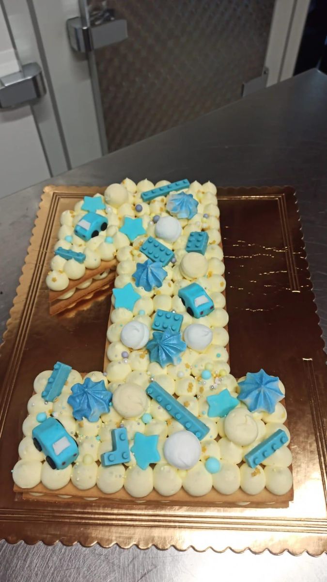 Cream tart a forma di 1 con decorazioni azzurre e ciuffi di crema