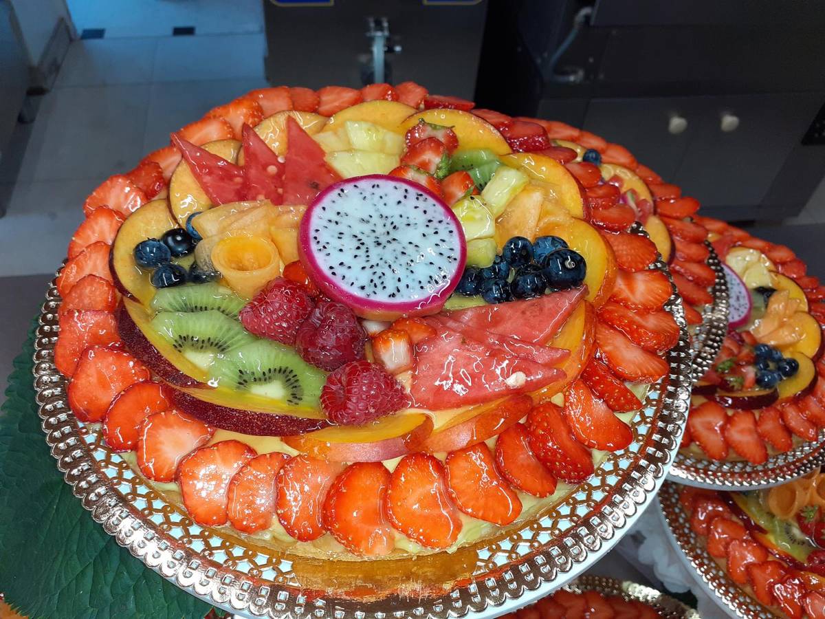 Crostata di frutta fresca con pitaya al centro, servita sull'alzata
