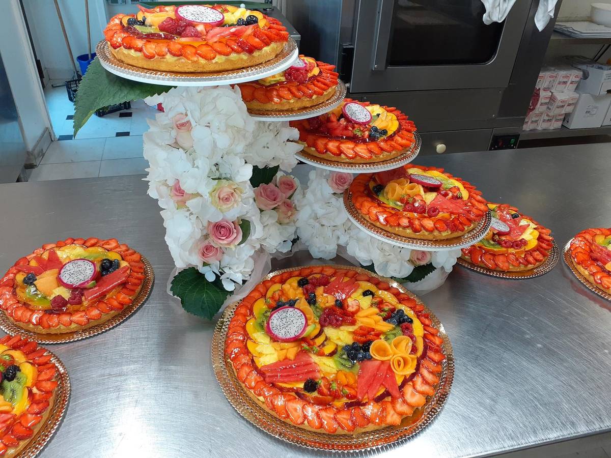 Crostate di frutta esposte sulle alzate con fiori bianchi
