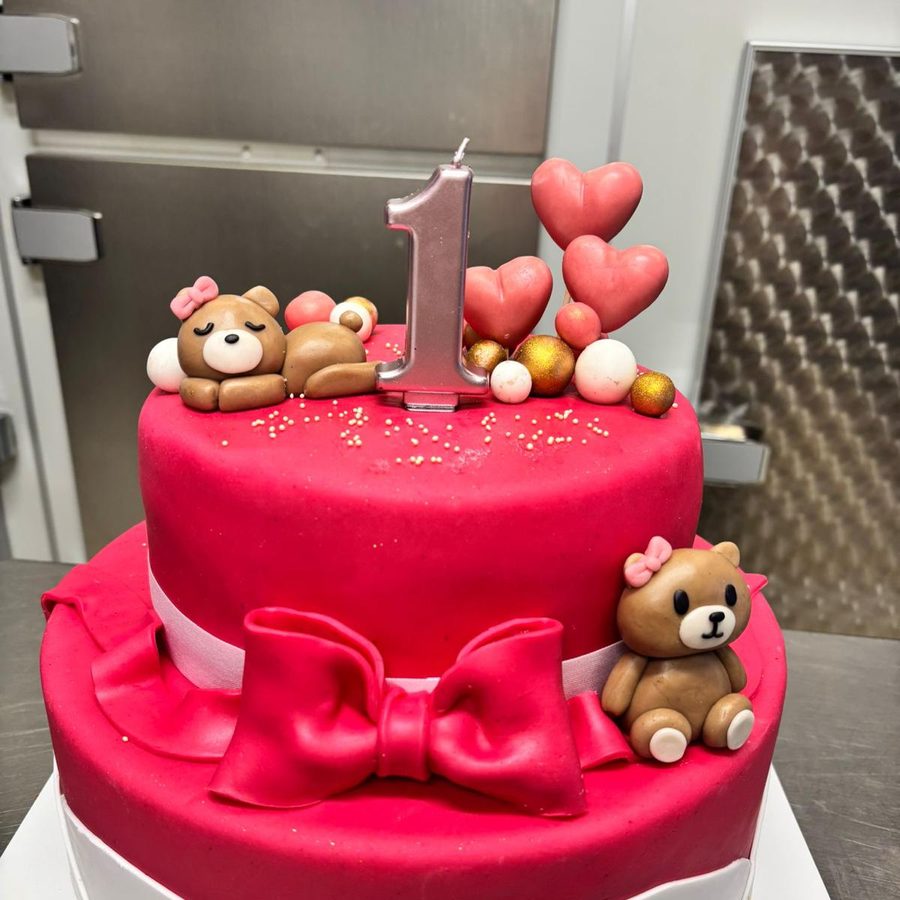 Torta di primo compleanno a due piani fucsia con fiocco, orsetti e candelina