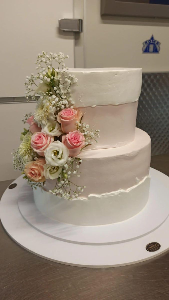 Torta nuziale a tre piani con rose rosa e velo da sposa