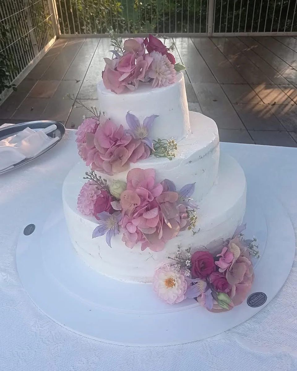 Torta nuziale a tre piani con ortensie e fiori rosa