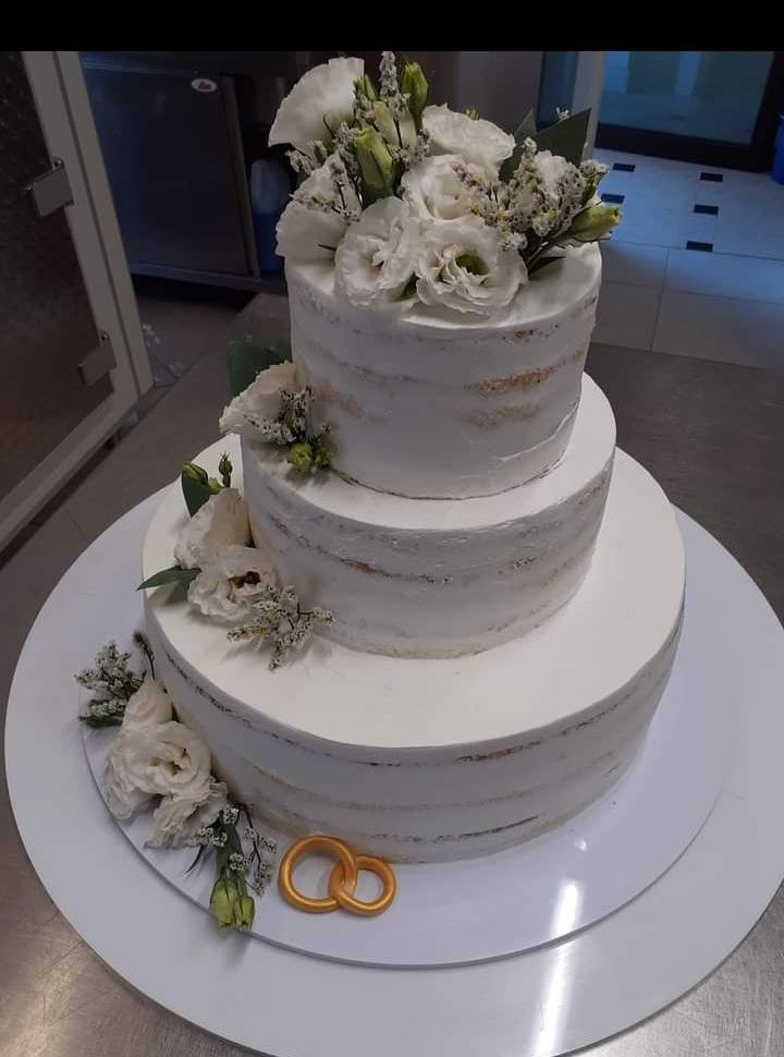 Torta nuziale a piani semi-nuda con fiori bianchi e fedi