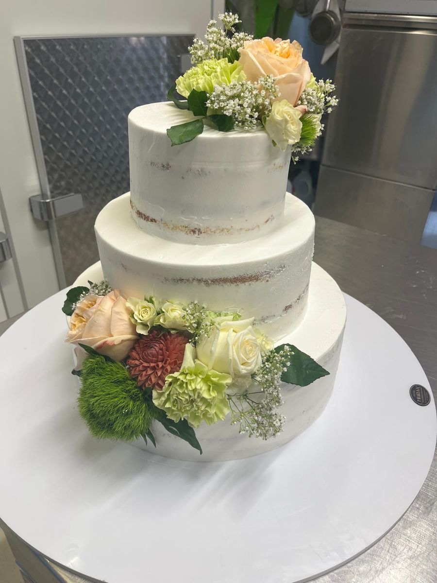 Torta nuziale a due piani con rose bianche e fiori di campo