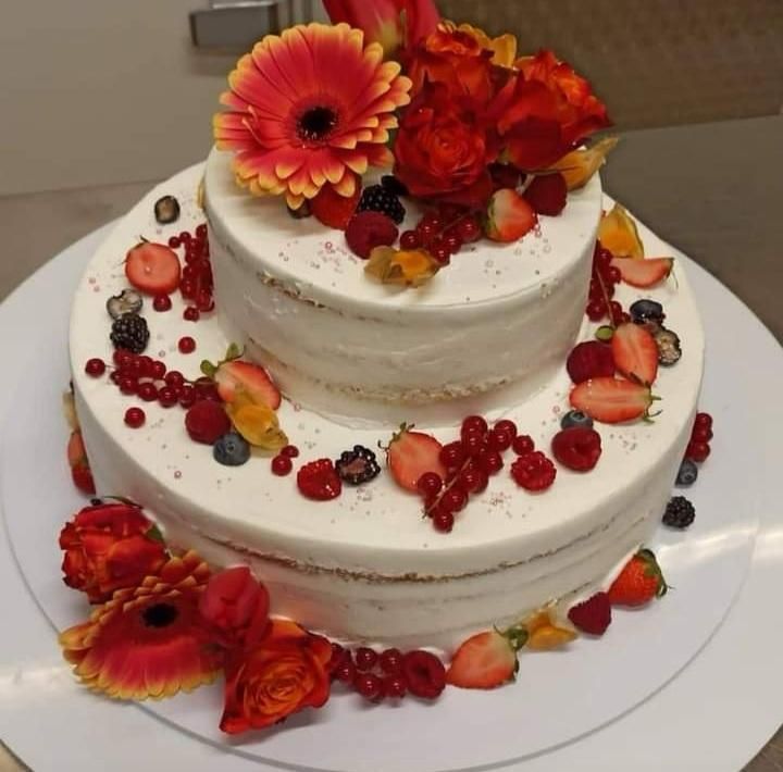 Torta nuziale a due piani con gerbere rosse, fragole e frutti di bosco