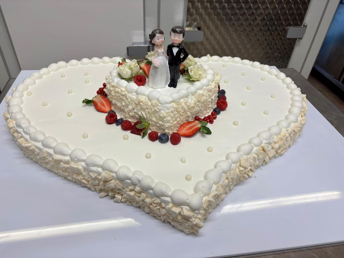 Torta nuziale a cuore con fragole, frutti di bosco e statuine degli sposi