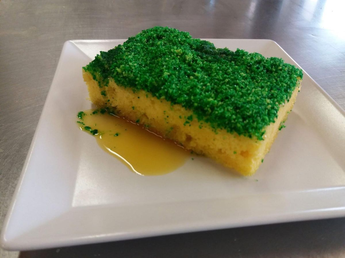 Fetta di torta con copertura verde e salsa all'arancia, servita al piatto